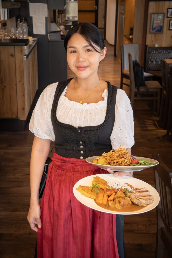 Servicekraft in Tracht mit Tellern im Dechbettener Hof